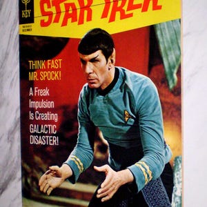 May include: Vintage Star Trek comic book cover featuring Mr. Spock. The cover has a yellow banner with the title "STAR TREK" in red. The comic book cover has the text "THINK FAST MR. SPOCK!" and "A Freak Impulsion Is Creating GALACTIC DISASTER!"