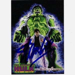 Puede incluir: Una tarjeta coleccionable con The Incredible Hulk. Hulk se representa como una figura grande, verde y musculosa con una expresión furiosa. Un hombre con bata de laboratorio está frente a Hulk. La tarjeta tiene el texto "The Incredible Hulk" y "Gallery Cards".