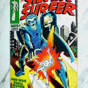 Könnte beinhalten: Comic-Cover von The Silver Surfer. Das Cover zeigt eine große Figur in Blau und Schwarz, mit dem Silver Surfer in Silber. Der Text enthält "Sky-Rider of the Spaceways!" und "And Who Shall Mourn For Him?"