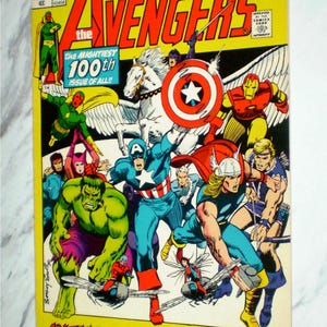 May include: A vintage Marvel Comics Avengers issue 100 comic book featuring a yellow cover with illustrations of The Hulk, Captain America, Thor, Iron Man, and other superheroes. The text reads Avengers, The Mightiest 100th Issue Of All, and Avengers Assemble! And We Do Mean Assemble!!