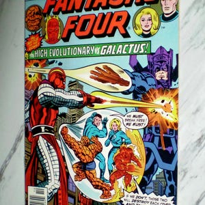 Puede incluir: Portada de cómic vintage de Fantastic Four #175. La portada presenta ilustraciones coloridas de superhéroes y villanos en acción, con el texto "The High Evolutionary vs. Galactus!"