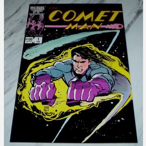 May include: Comic book cover for "The Comet Man" with a male character in a blue and purple suit, set against a black backdrop with a yellow energy field. The title is in yellow and pink, with the Marvel Comics logo in the top left corner.