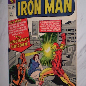 May include: Vintage comic book cover of "Tales of Suspense" featuring Iron Man. The cover art shows Iron Man in a red and gold suit, battling a villain. The comic is marked with the Marvel Comics logo and the number 56.