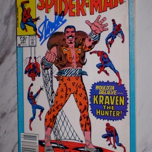Puede incluir: Portada de cómic de Marvel Tales Spider-Man con Kraven el Cazador. La ilustración muestra a Kraven en naranja y marrón, con figuras de Spider-Man en acción. El cómic está firmado por Stan Lee y John Romita.