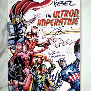 May include: A comic book cover for Marvel's Avengers, featuring multiple superheroes in action. The title "The Ultron Imperative" is prominently displayed. The cover includes signatures and the text "Direct Edition".