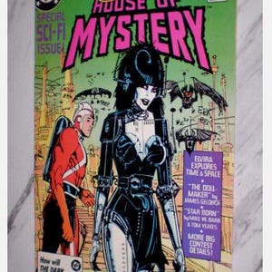 May include: A comic book cover for "Elvira's House of Mystery" features Elvira in a black outfit with a futuristic design. The cover is predominantly green and pink, with the DC Comics logo and text that reads "Special Sci-Fi Issue."