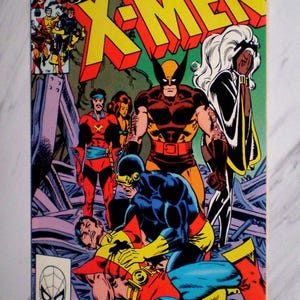 May include: A vintage comic book cover for Marvel Comics Group's "The Uncanny X-Men". The artwork depicts several costumed superheroes, including Wolverine and Storm, in a dramatic battle scene. The title is in bold yellow and red lettering.