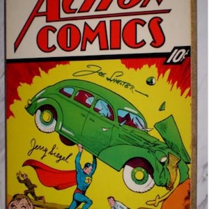 May include: Vintage "Action Comics" No. 1 comic book cover. The cover features Superman lifting a green car, with the title in red and yellow. The date "June, 1938" is visible. The comic is a classic piece of pop culture.