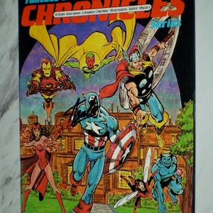 May include: A comic book cover featuring various superheroes, including Iron Man, Captain America, and Thor. The title reads "FantaCo's Chronicles" with the text "This Issue: The History of The Avengers." The cover is predominantly black with colorful illustrations.
