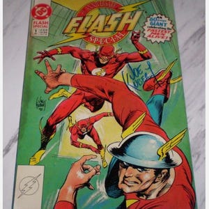 May include: A vintage comic book cover featuring the Flash in a dynamic pose. The cover is predominantly red, yellow, and blue, with the title "Flash Special" prominently displayed. The comic book cover has the text "80 page GIANT celebrating the FASTEST MEN ALIVE!"