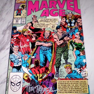 May include: A vintage Marvel Age comic book featuring various superheroes. The cover displays the title in large pink letters, with illustrations of characters like Thor and Spider-Man. The comic is signed by Tom Palmer.