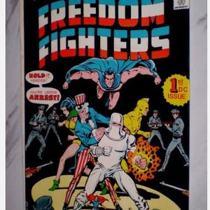 Puede incluir: Una portada de cómic vintage de "Freedom Fighters" con superhéroes en acción. La portada tiene un fondo negro con texto e ilustraciones en rojo, blanco y azul. Es el primer número.