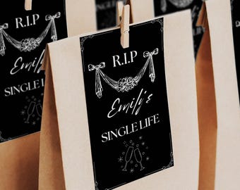 May include: Kraft paper gift bags with black tags that read "R.I.P. Emily's SINGLE LIFE". The tags are held in place with small wooden clothespins. The tags have a decorative floral design and champagne glasses.