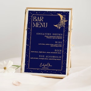 May include: A gold framed sign with a navy blue background and gold stars. The sign says "Bar Menu" and lists signature drinks, wine, beer, and non-alcoholic options. The sign also features a gold crescent moon with floral details.