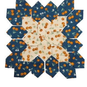 May include: A handmade patchwork quilt square featuring a floral design. The quilt square is composed of various geometric shapes in a repeating pattern. The fabrics used include a dark blue with orange cherries and a cream color with orange cherries.