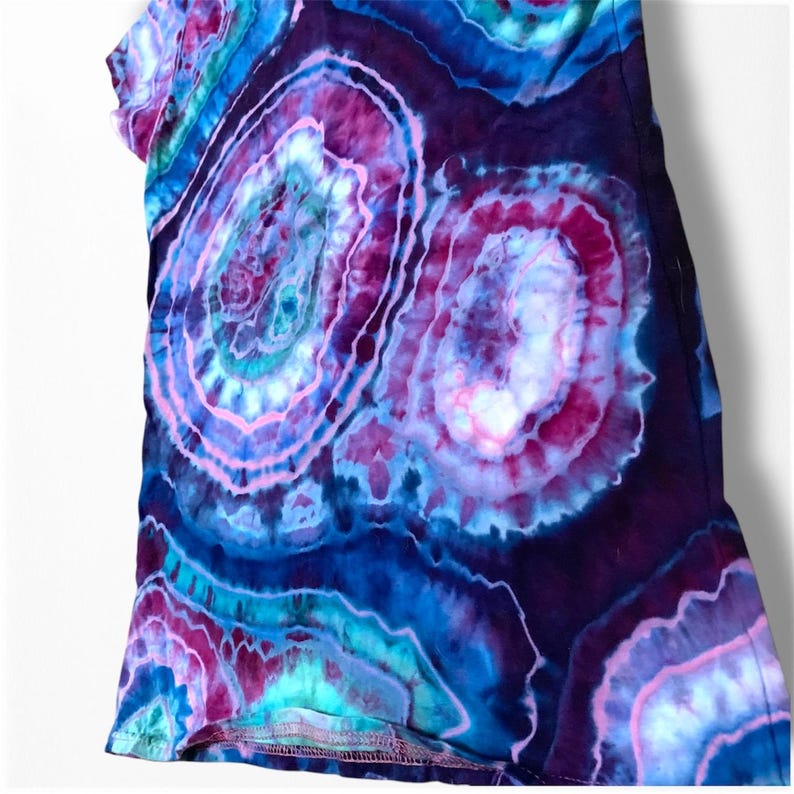 May include: A tie-dye shirt with a swirling pattern of pink, blue, and purple. The shirt has a relaxed fit and a crew neck.