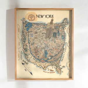 May include: A framed map of New York City, illustrated in a vintage style. The map is detailed with landmarks, streets, and the surrounding areas of the United States. The frame is made of light-colored wood, and a seagull is depicted in the lower left corner.