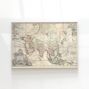 May include: Framed vintage map of Asia, with detailed cartography in various colours. The map includes geographical features, text, and decorative elements, all within a white frame. A historical piece.
