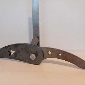 May include: A metal tool with a curved blade and a star-shaped cutout. The tool is attached to a metal rod with a bolt.