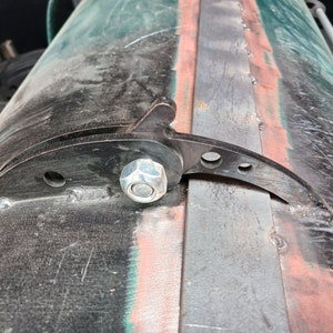 Peut inclure: Gros plan sur un loquet métallique avec un écrou argenté et un bras en métal noir. Le loquet est fixé à une surface métallique rouillée.