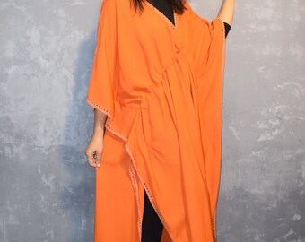 Puede incluir: Un vestido caftán naranja con cuello en V y cintura ceñida. El vestido tiene un diseño fluido con laterales abiertos y se combina con leggings negros y sandalias. El vestido tiene un ribete decorativo a lo largo de los bordes.