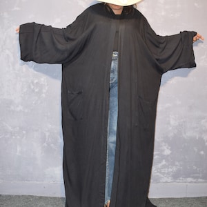 May include: A long black cardigan with a wide open front and two pockets. The cardigan is made of a soft, flowing fabric.