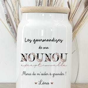 Puede incluir: Tarro de cerámica blanco con tapa de madera. El tarro tiene el texto "Les gourmandises de ma NOUNOU exceptionnelle" y "Merci de m'aider à grandir !" con un corazón y el nombre "Léna".