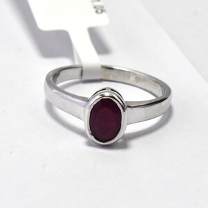 May include: A silver ring with a red oval gemstone.