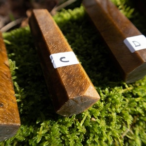 May include: Four brown, faceted, crystal-shaped stones with white labels. The labels are marked with the letters A, B, C, and D.