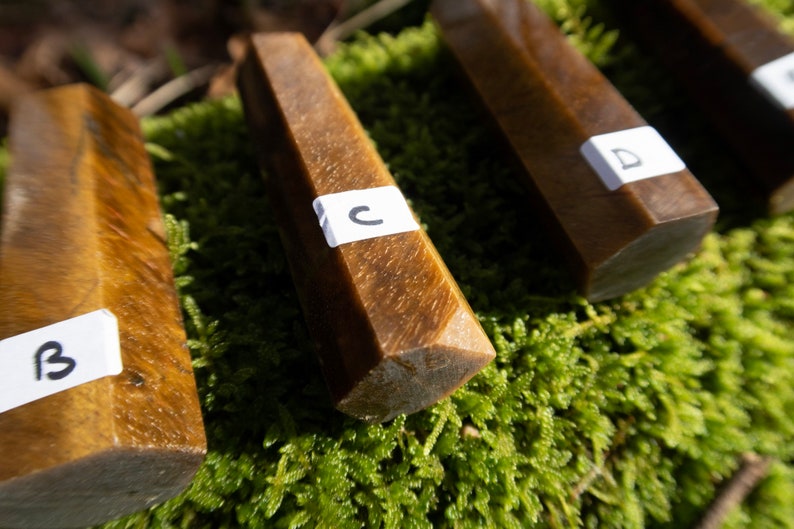 May include: Four brown, faceted, crystal-shaped stones with white labels. The labels are marked with the letters A, B, C, and D.