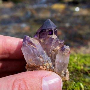 May include: A cluster of amethyst crystals with a purple hue. The crystals are pointed and have a natural, rough texture.