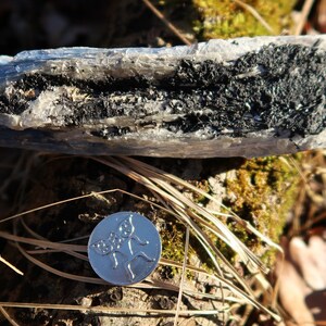 May include: A close-up of a blue and black crystal with a silver coin featuring a floral design in the foreground.