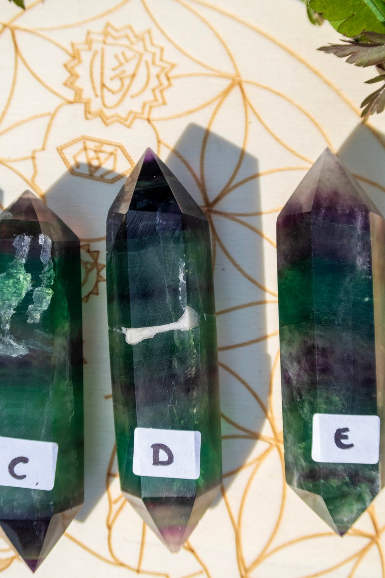 May include: Three green and purple fluorite crystal points with white markings. The points are labeled C, D, and E.