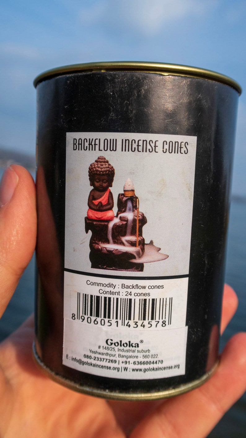 May include: A black metal tin with a gold lid containing 24 backflow incense cones. The label features a small Buddha statue and the text "Backflow Incense Cones" and "Goloka".