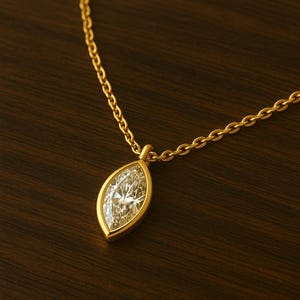 May include: A gold chain necklace with a marquise-shaped diamond pendant.