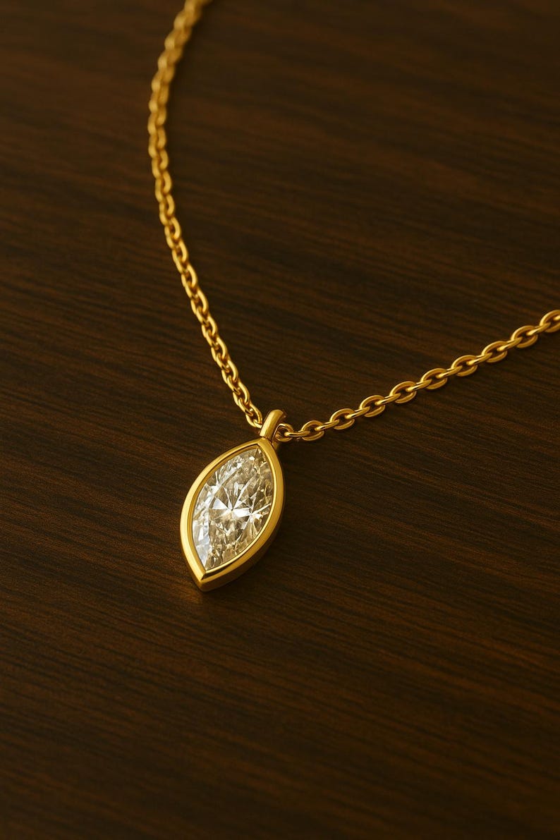 May include: A gold chain necklace with a marquise-shaped diamond pendant.