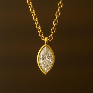 May include: A gold chain necklace with a marquise-shaped diamond pendant.
