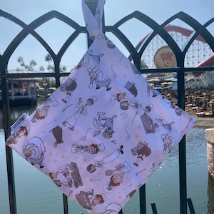 May include: A white reusable wet bag with a colorful print of cartoon chefs and a mouse. The bag has a zipper closure and a hanging loop.