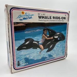 Może przedstawiać: Prostokątne kartonowe pudełko na dmuchaną zabawkę basenową The Wet Set Whale Ride-On. Pudełko zawiera grafikę czarno-białej orki w basenie, z tekstem wskazującym wymiary 83 na 46 cali oraz informację o 2 komorach powietrznych w produkcie.