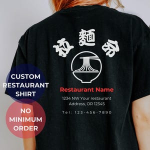 May include: Black t-shirt with a white design of a bowl of noodles and Chinese characters. The text "Restaurant Name", an address, and a phone number are printed below the design.