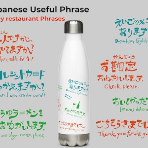 Könnte beinhalten: Eine weiße Edelstahl-Wasserflasche mit japanischen Sätzen darauf gedruckt. Die Sätze sind in Grün, Orange und Blau. Die Sätze übersetzen sich mit "Haben Sie eine Speisekarte in Englisch?", "Bitte die Rechnung", "Es war köstlich", und "Danke für das gute Essen".