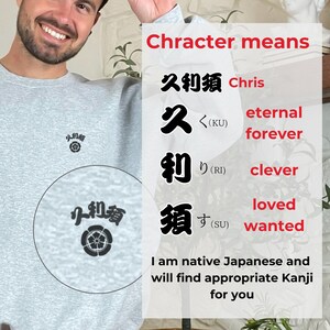 以下が含まれることがあります： 黒い日本語の文字のデザインが施された灰色のスウェットシャツ。文字は「久利須」と書いてあり、「永遠、賢い、愛されている、望まれている」という意味です。画像の上部には赤い文字で「Chracter means」と書かれています。