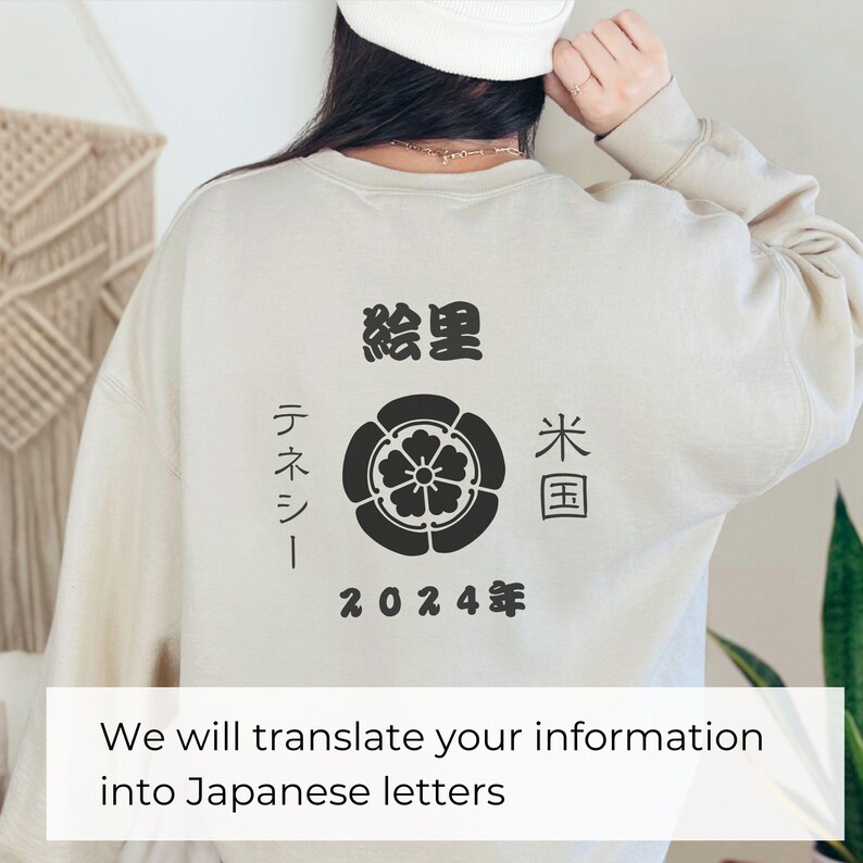 以下が含まれることがあります： 花柄の黒いプリントと黒い文字が書かれたベージュのトレーナー。文字は「絵里」「テネシー」「米国」「2024年」と書いてある。