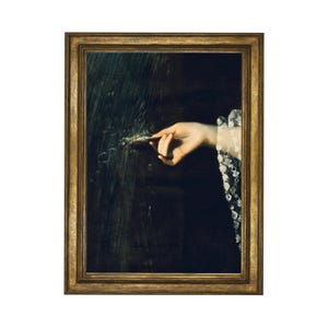 Puede incluir: Una pintura enmarcada de una mano que se extiende hacia un fondo oscuro y texturizado. La mano lleva una manga blanca de encaje.