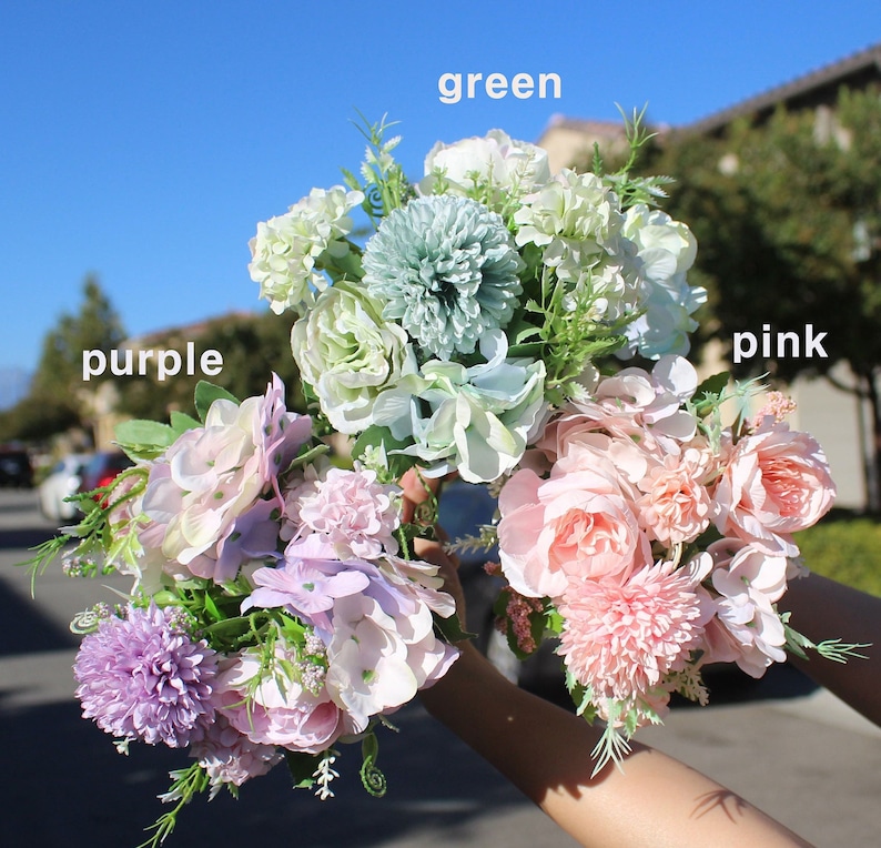 May include: Three bouquets of artificial flowers in shades of purple, green, and pink. The bouquets include roses, hydrangeas, and other floral arrangements. The word "purple", "green", and "pink" are written above each bouquet.