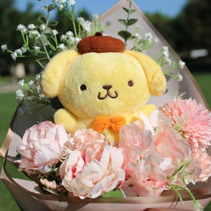 May include: A yellow plush toy dog wearing a brown hat is surrounded by pink and white flowers in a bouquet. The bouquet is wrapped in brown paper with a gold ribbon.