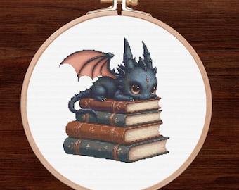 May include: A small, blue dragon with pink wings sits on a stack of four books. The dragon has large, dark eyes and a small, pointed snout.