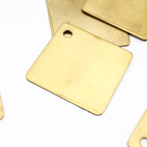 May include: A group of five brass square tags with rounded corners. One tag has a small hole in the center.