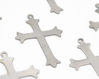 May include: Five silver metal cross charms with a decorative design. The charms have a hole at the top for hanging.