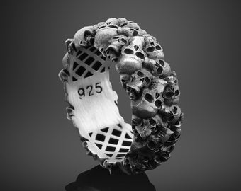 May include: A silver ring featuring a design of numerous skulls. The ring is marked with the number 925.